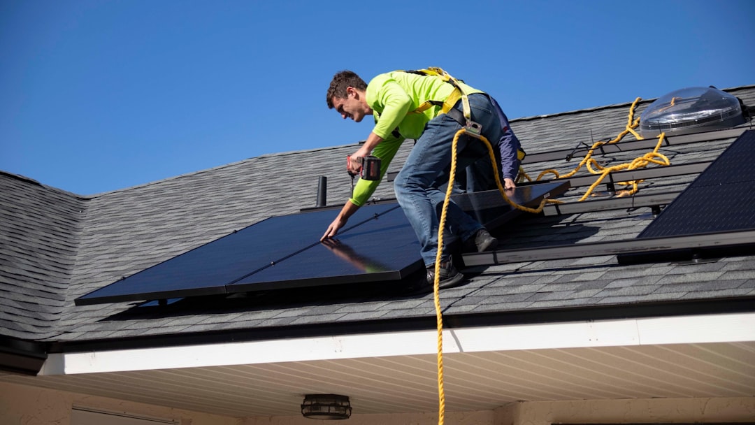 Worker installing solar panels on a sloped residential roof