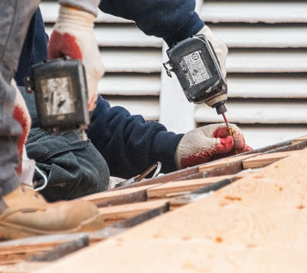 Roof Installation Work Construction workers using power drills on a roof