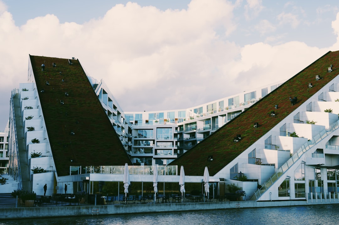 Modern architectural complex with triangular roofs and a waterfront promenade