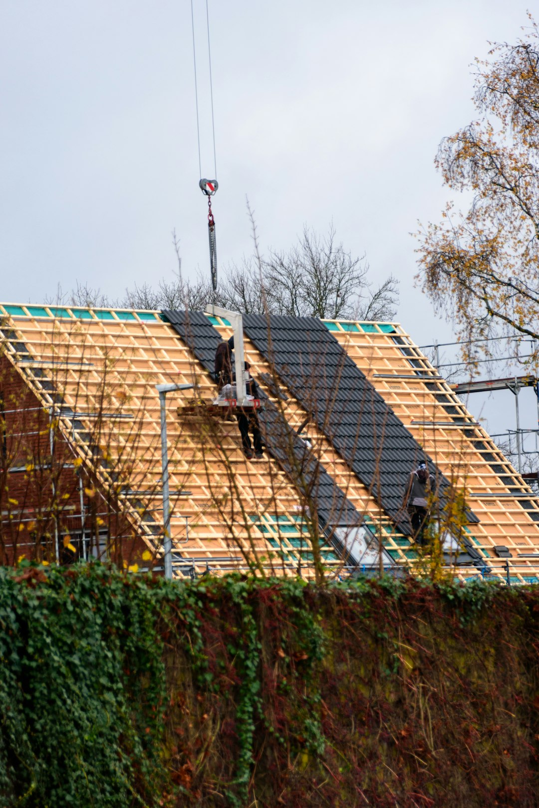 Roof Installation in Taylor Workers installing roofing tiles on a house under-construction house.