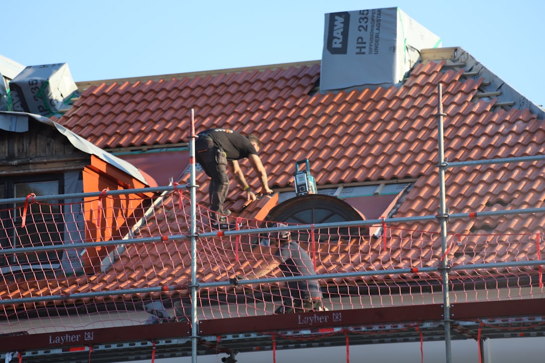 Construction worker handling tiles on a red clay tile roof