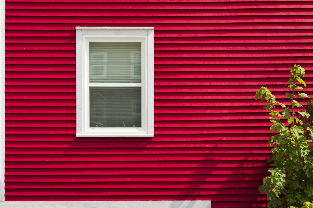 a red building with a white window and a tree