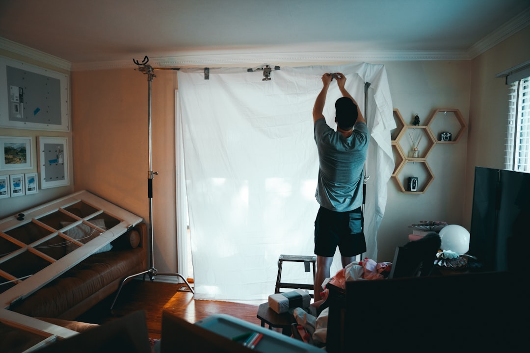 Man Adjusting Backdrop man standing beside white curtain