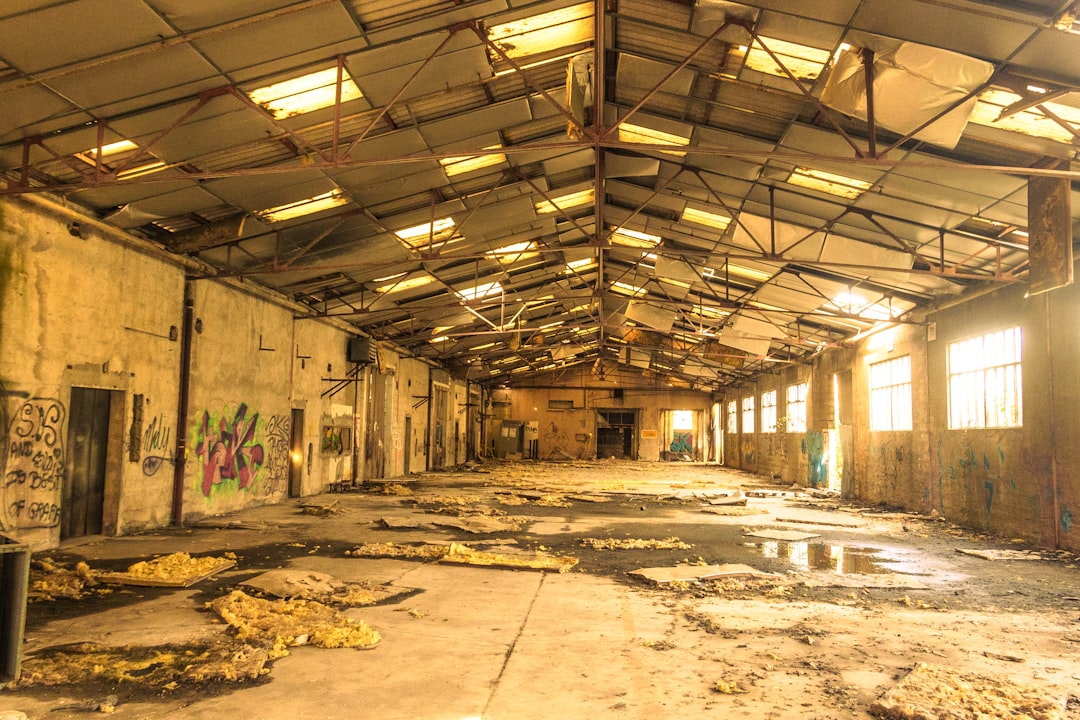 Industrial Warehouse Interior Empty, decaying industrial warehouse with broken roof and debris.