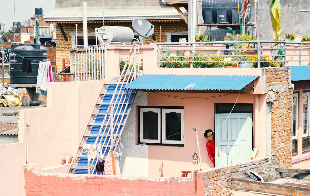 Woman at Doorway of House person peeking behind white wooden door during daytime