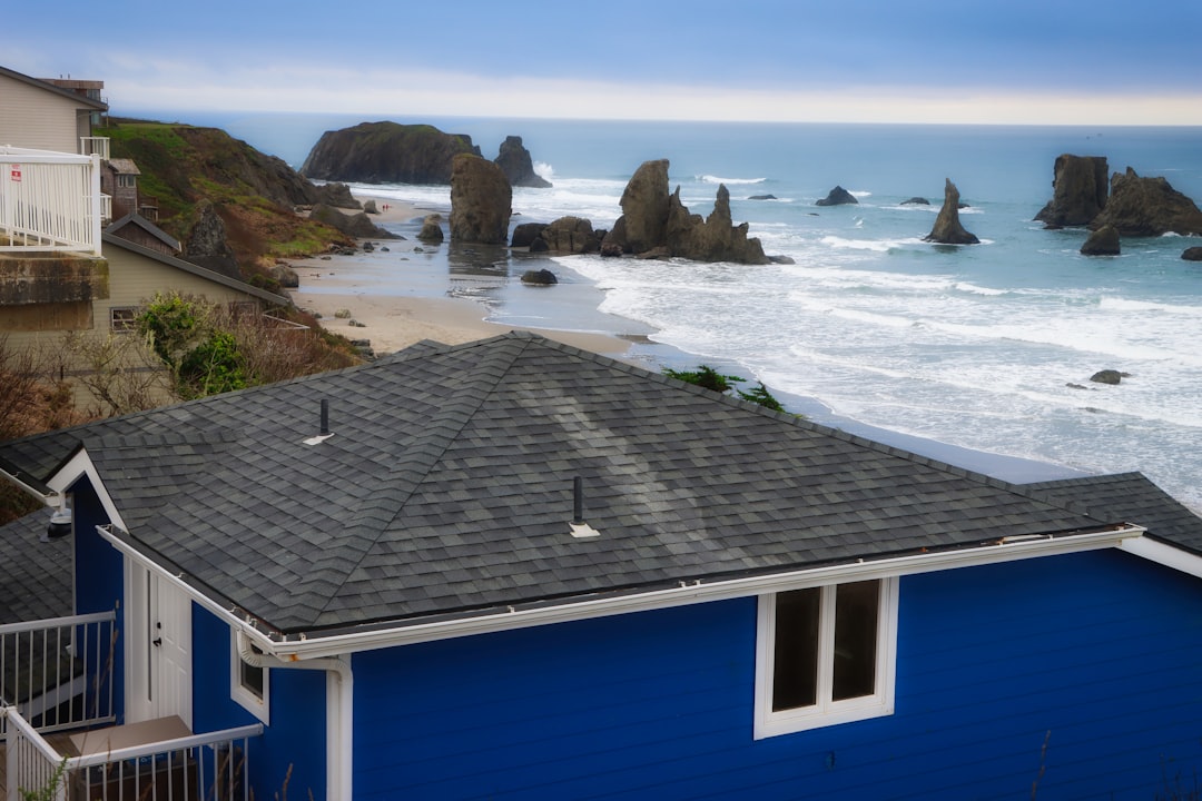 Blue house overlooks rocky coastline and ocean waves