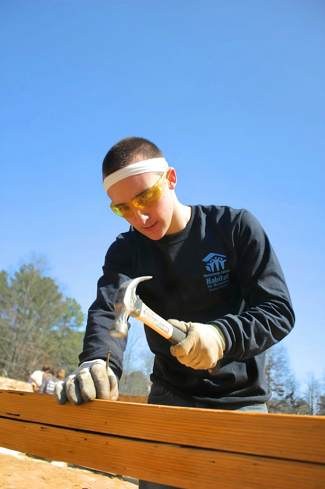 Individual hammering a nail into lumber at a construction site