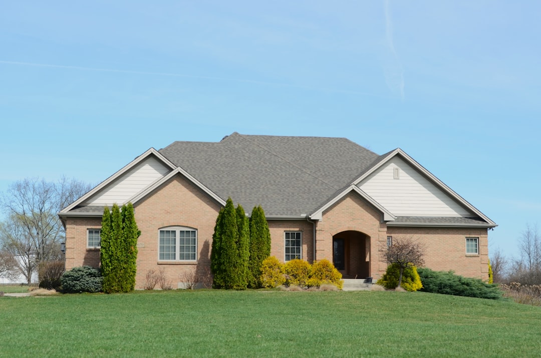 Suburban Brick House with Shingled Roof A suburban brick house with a well-kept lawn.