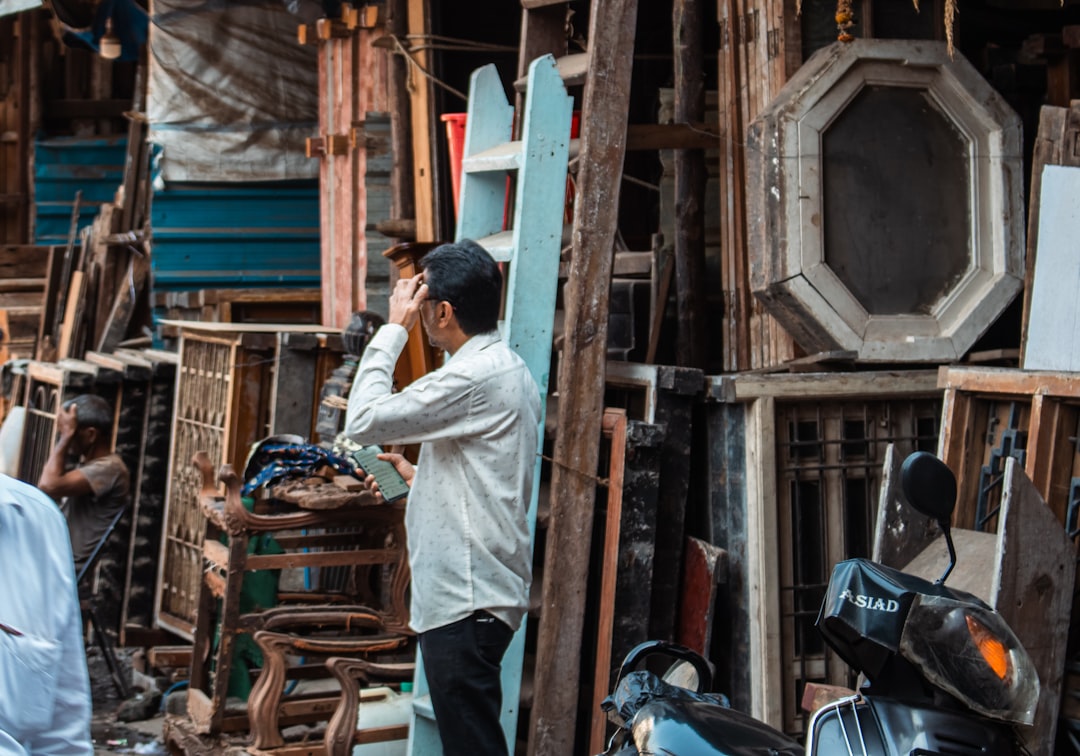 Man looking through old windows at an outdoor market.