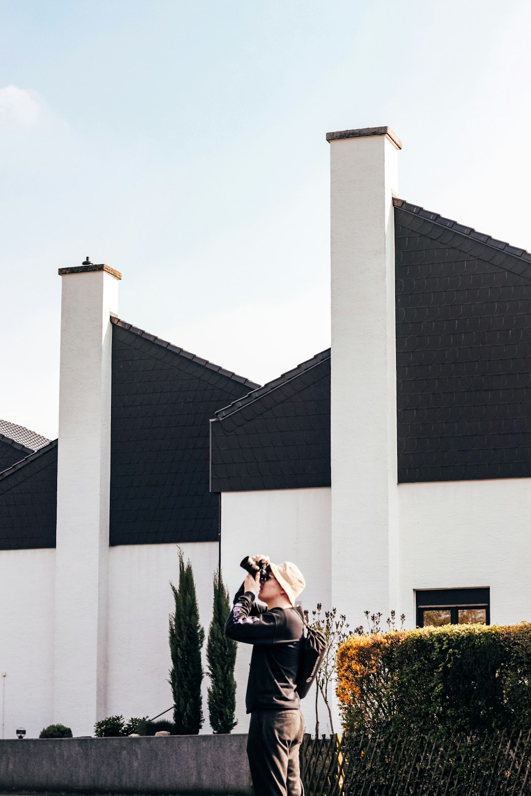 Person Photographing Building woman in black jacket sitting on green grass during daytime