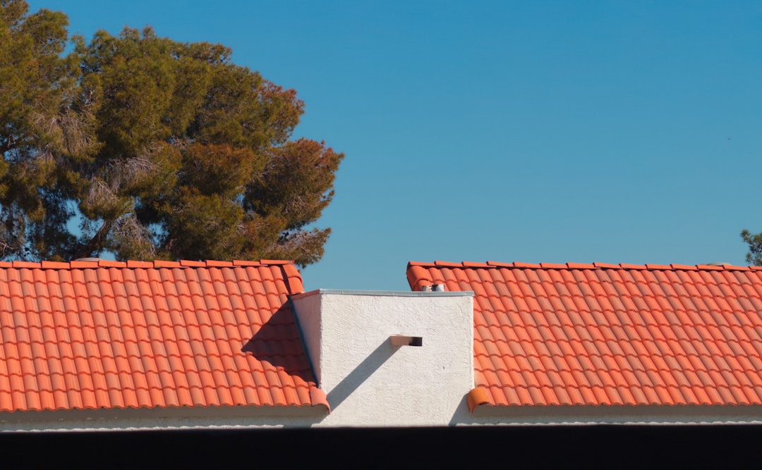 Two orange tiled roofs with a white chimney.