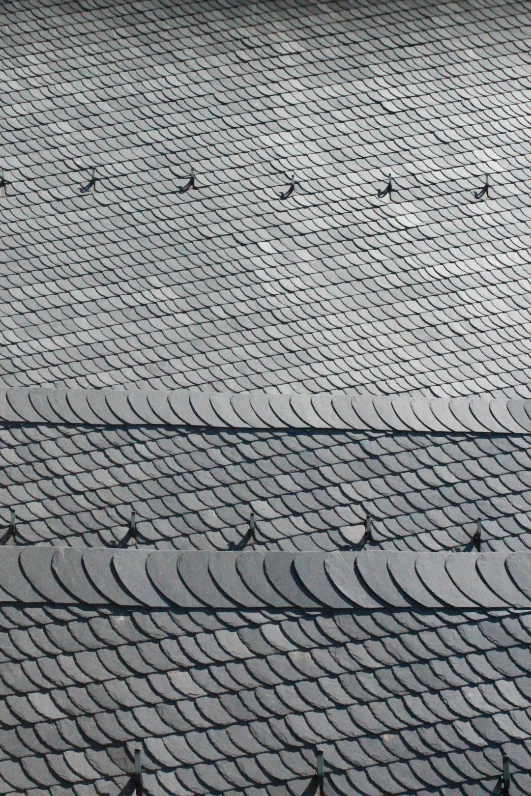 Slate Roof Close-Up Textured dark gray slate roof with diamond and scalloped patterns.