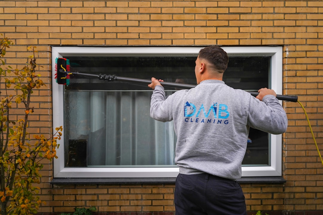 A man holding a baseball bat in front of a window