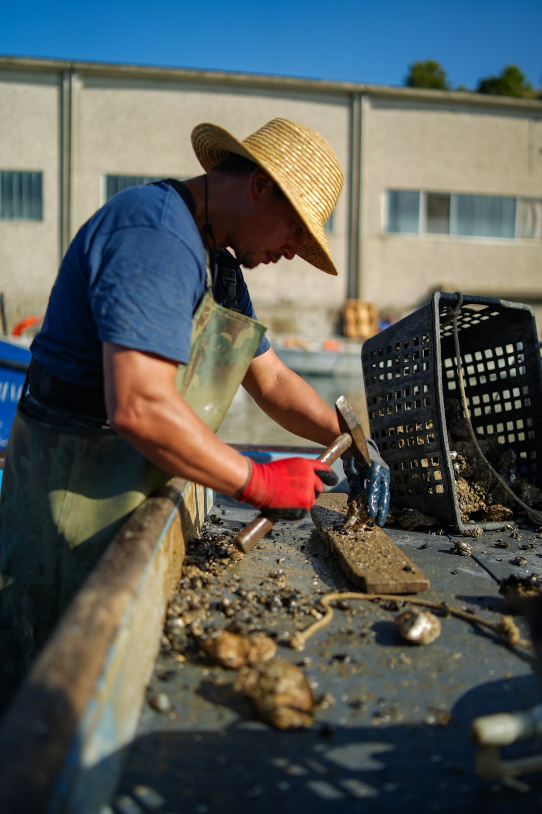 a man in a straw hat working on a piece of metal