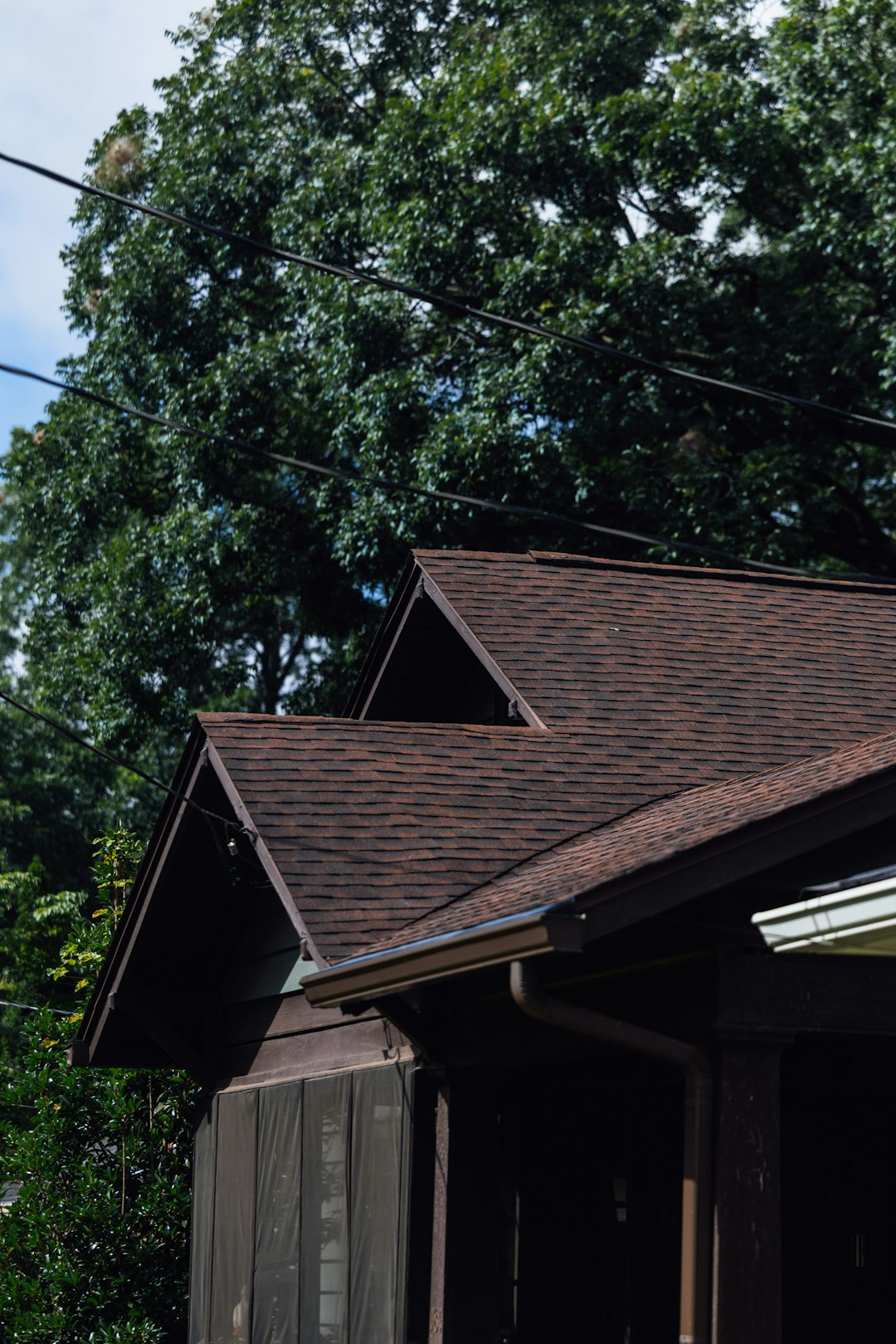 Brown Shingle Roof Installation A brown shingled roof with green trees and power lines.