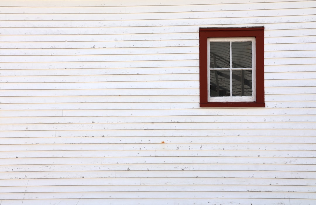 White Siding With Window White siding with a window that has a red frame.