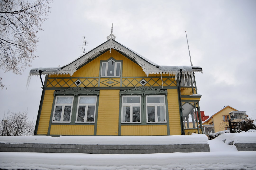 A yellow house with icicles in the snow