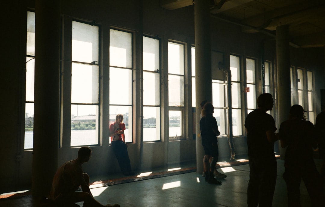 059810c79fc14d4393ef00fd4d16791e People silhouetted against large windows with sunlight streaming in