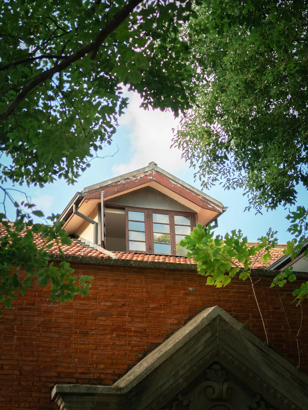 07e6a45564ce4e0c8290ab1cfd64e60b Brick building with dormer window under trees