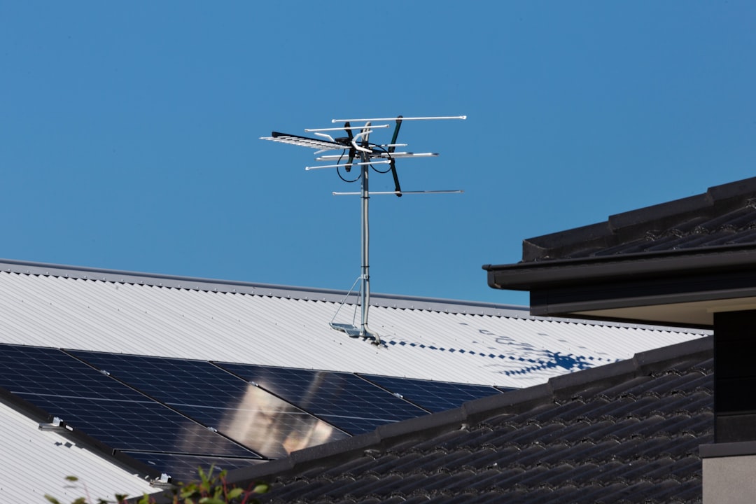 A television antenna stands tall against a clear blue sky