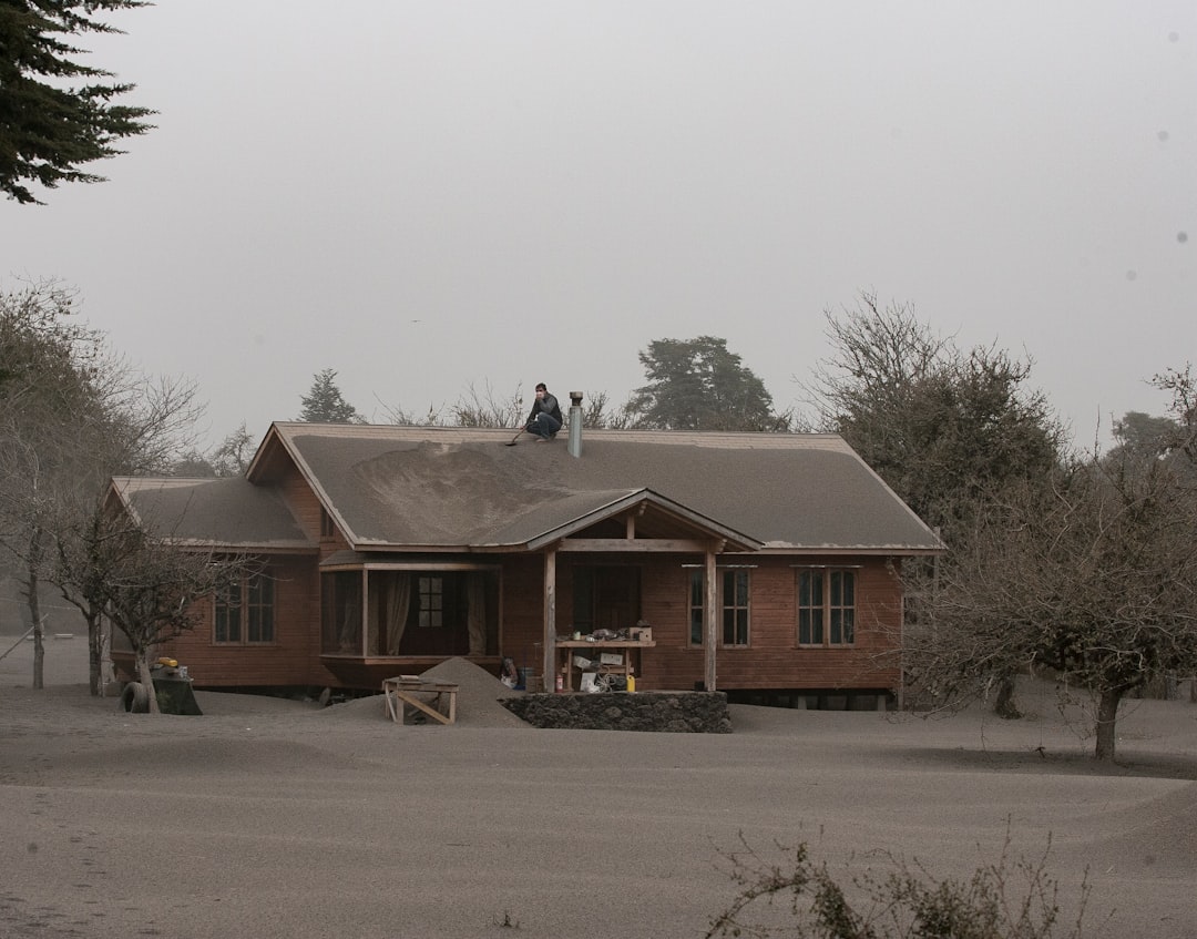 People cleaning volcanic ash from a house roof.