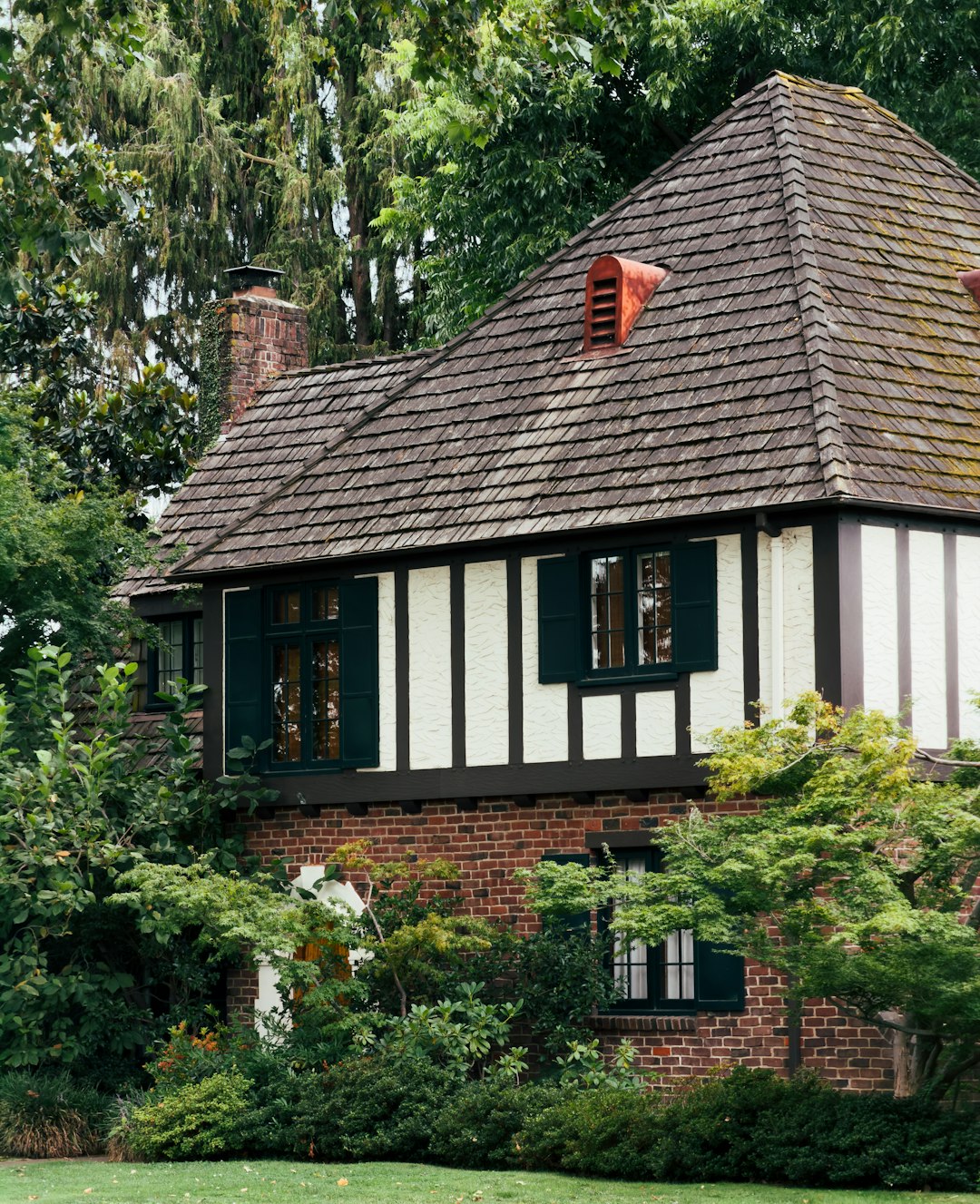A charming tudor-style house surrounded by lush green foliage