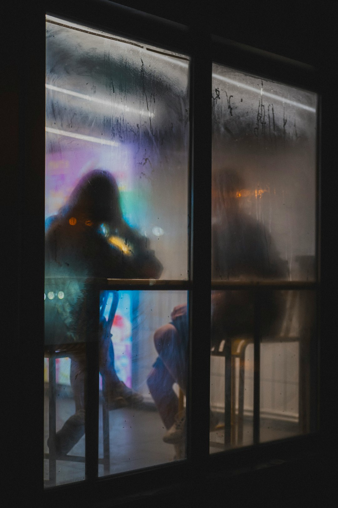 1d648b99dad24c7c8bb973495c878cc5 People sit inside, seen through a foggy window