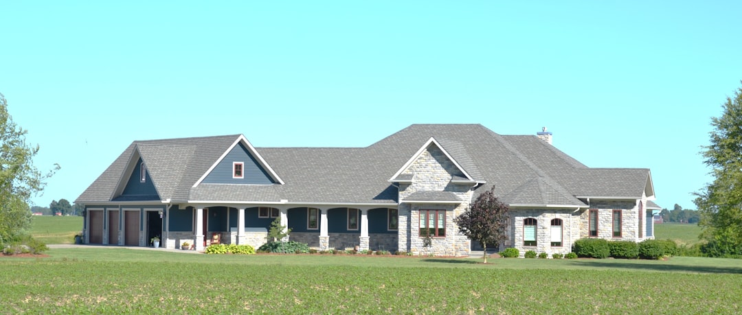 Large House with Gabled Roof Large modern house with gray roof in a green field.
