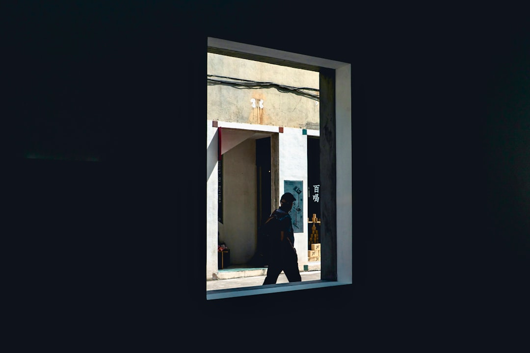 Silhouetted person walking past a bright window.