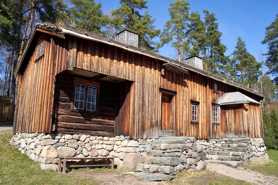 3302d0bb07a84bb39ae1028114cf8677 a wooden building with a stone wall and a bench in front of it