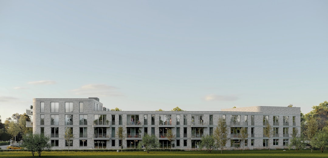 Modern residential building with balconies, surrounded by green trees.