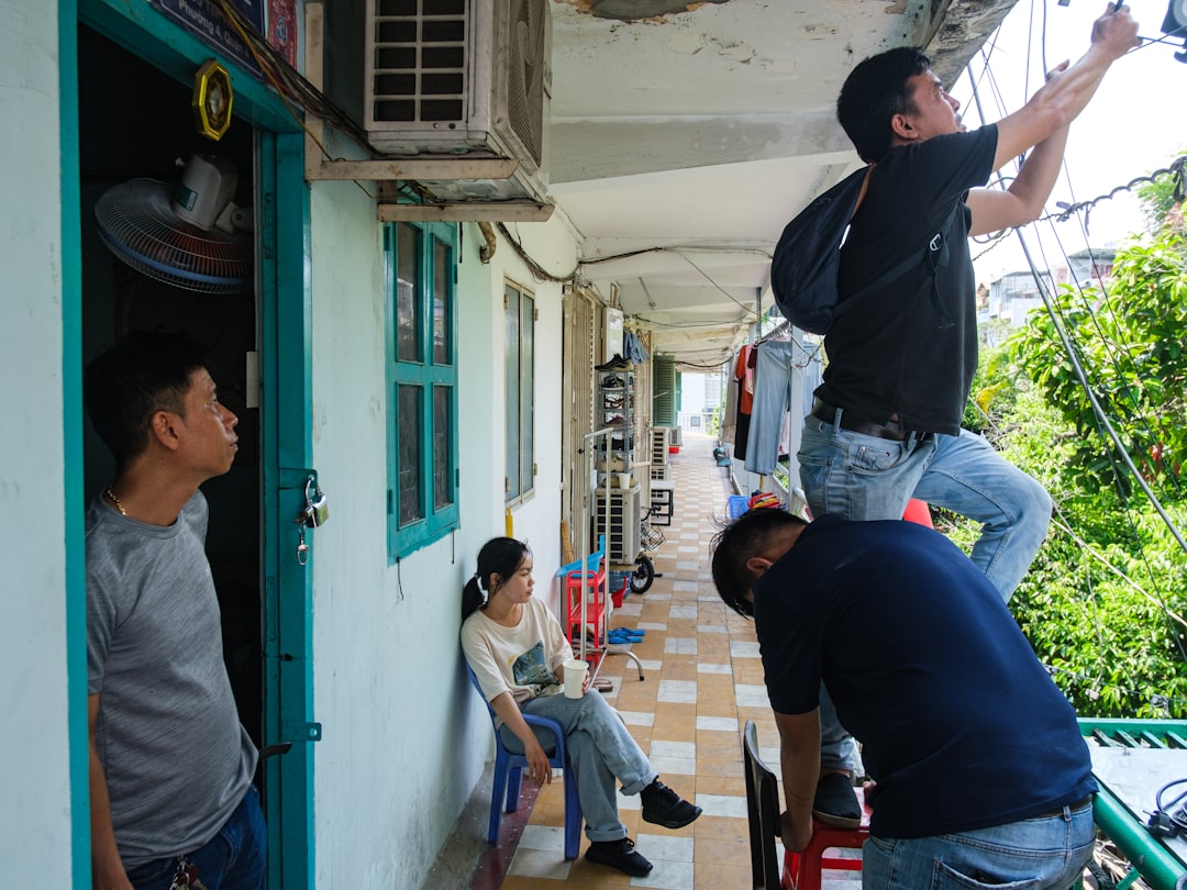 Men repairing wires on a crowded residential building balcony.