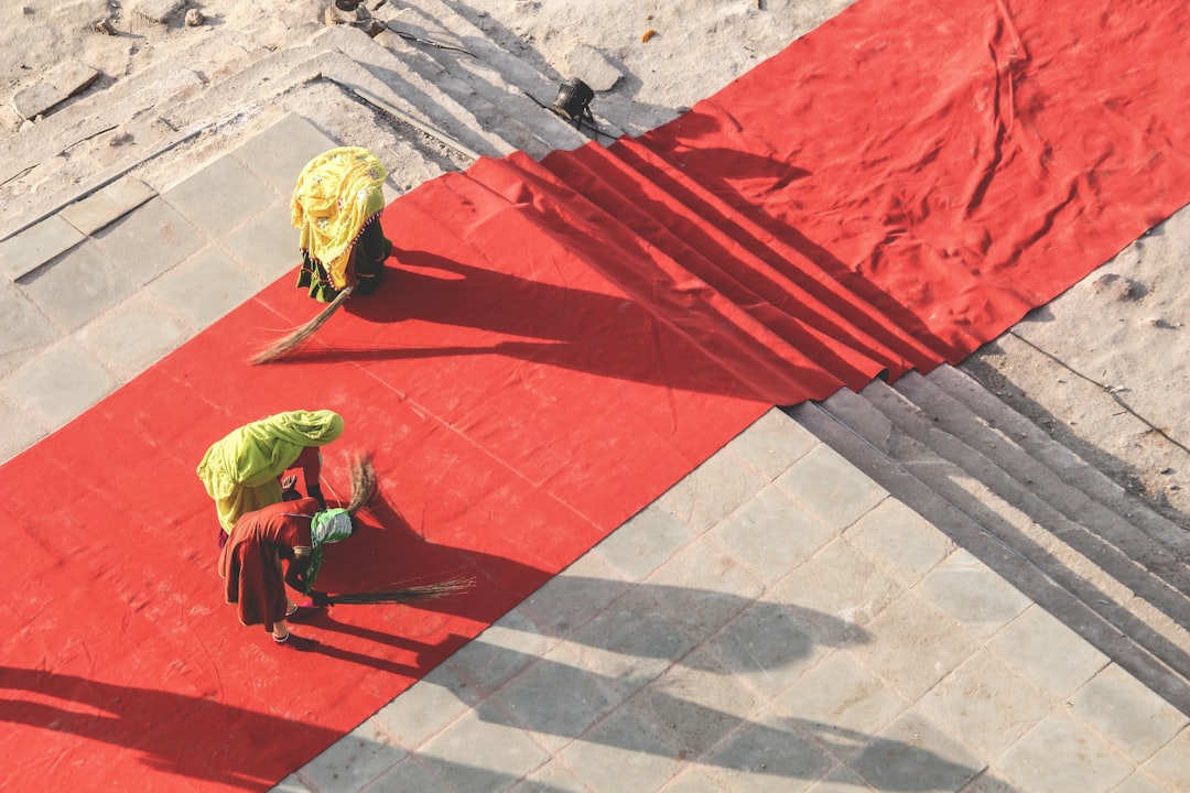 3da8eeda0aaa4b53897f48d5caa218ab man in green shirt and black pants walking on red concrete floor during daytime