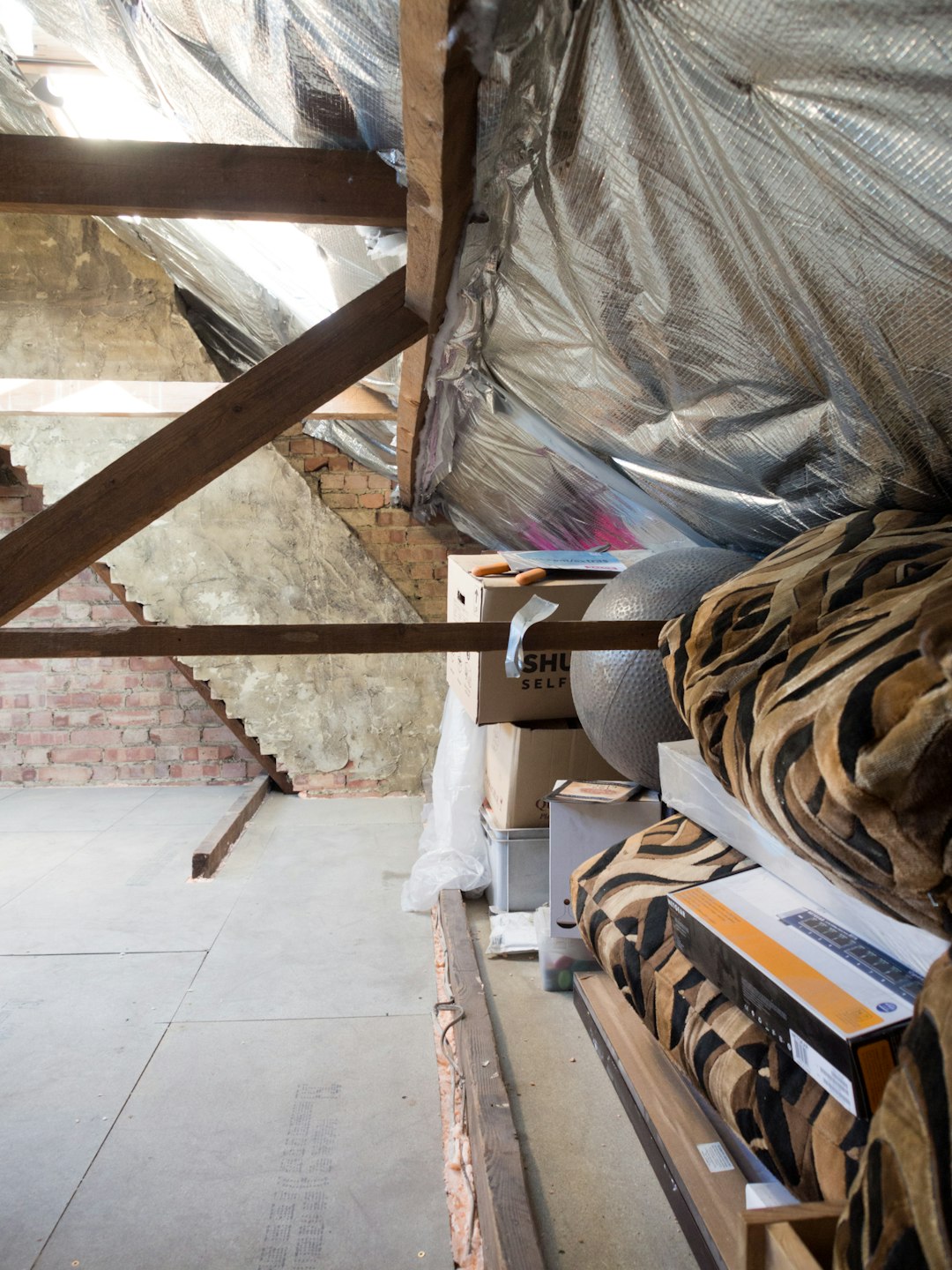An attic filled with boxes, insulation, and beams.