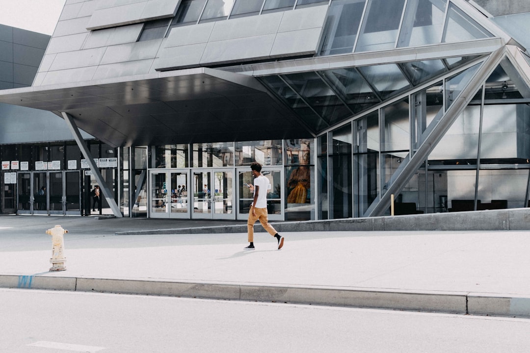 man in white t-shirt walking beside building during daytime