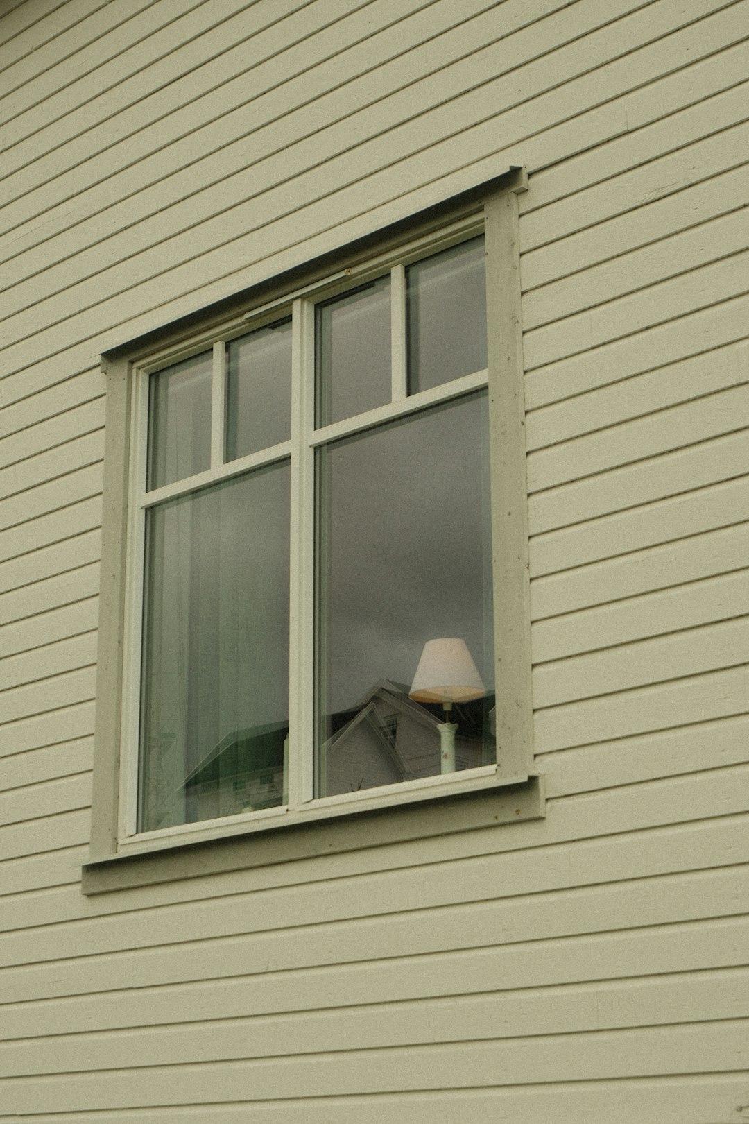 A window on a wooden house with a lamp inside.
