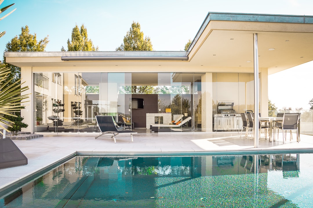A modern house with glass walls beside a swimming pool on a sunny day