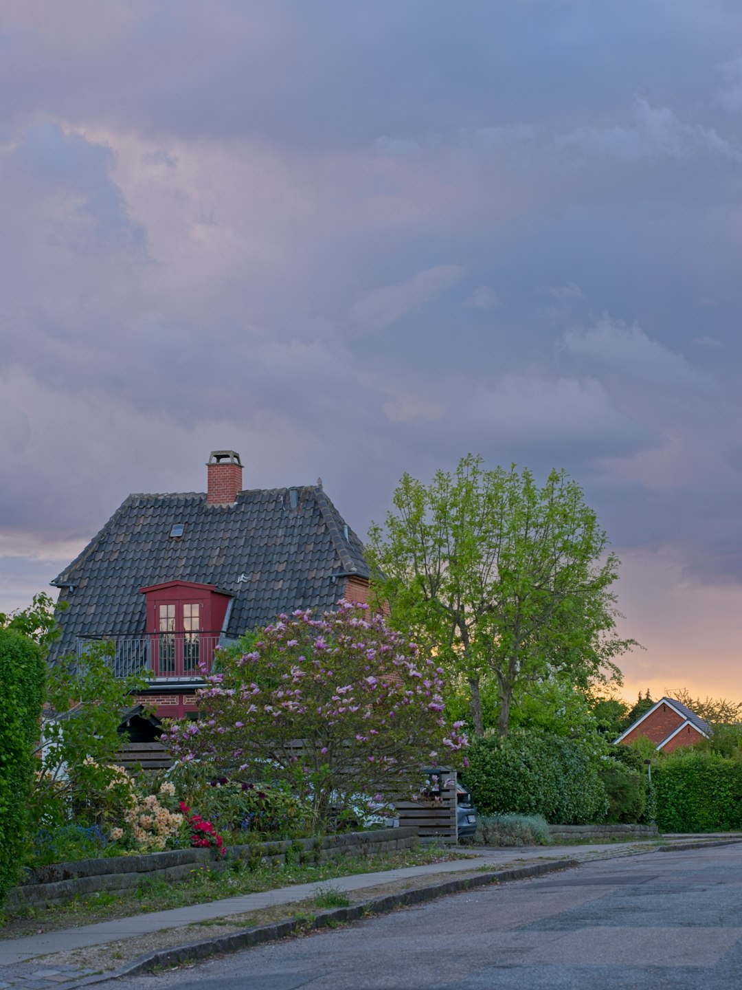 5de86d9302904400b78211c265db3724 Charming house and garden under a dramatic cloudy sunset sky.