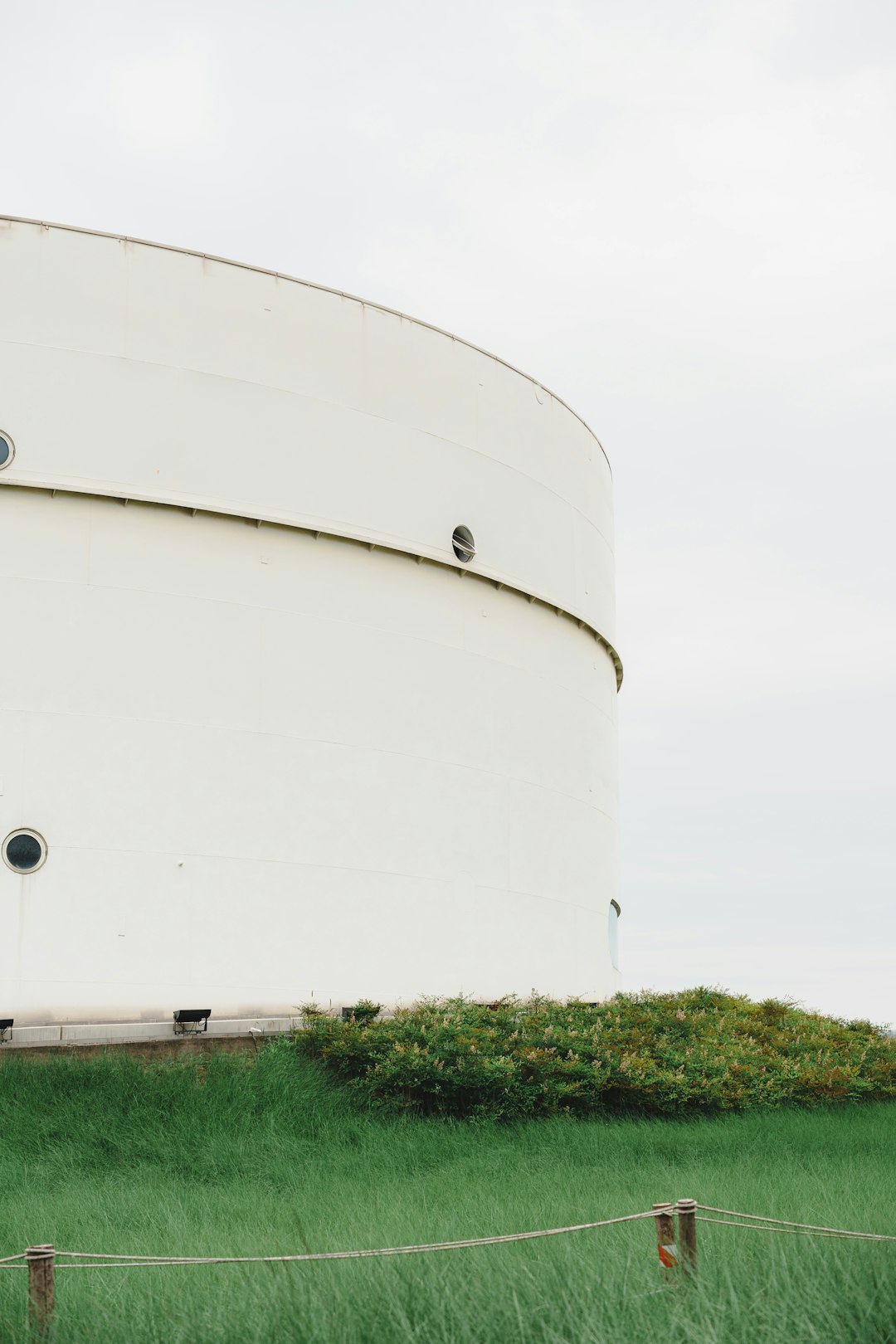 White curved building with round windows and green grass.