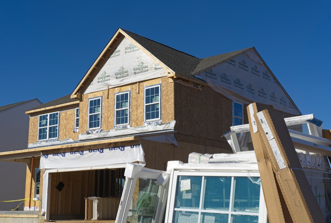69f4b2ab040c4b96b4e3a7f5a0d7160d A house under construction with plywood walls and stacked windows in the foreground