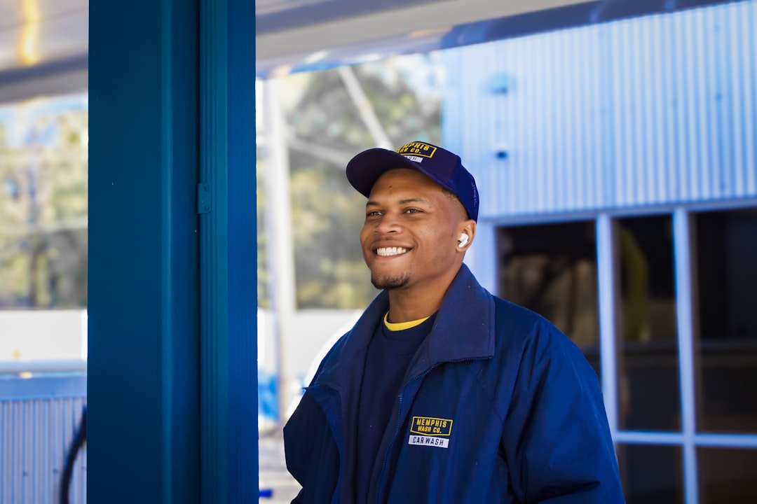 Man at Memphis Car Wash A man in a blue uniform standing in front of a building