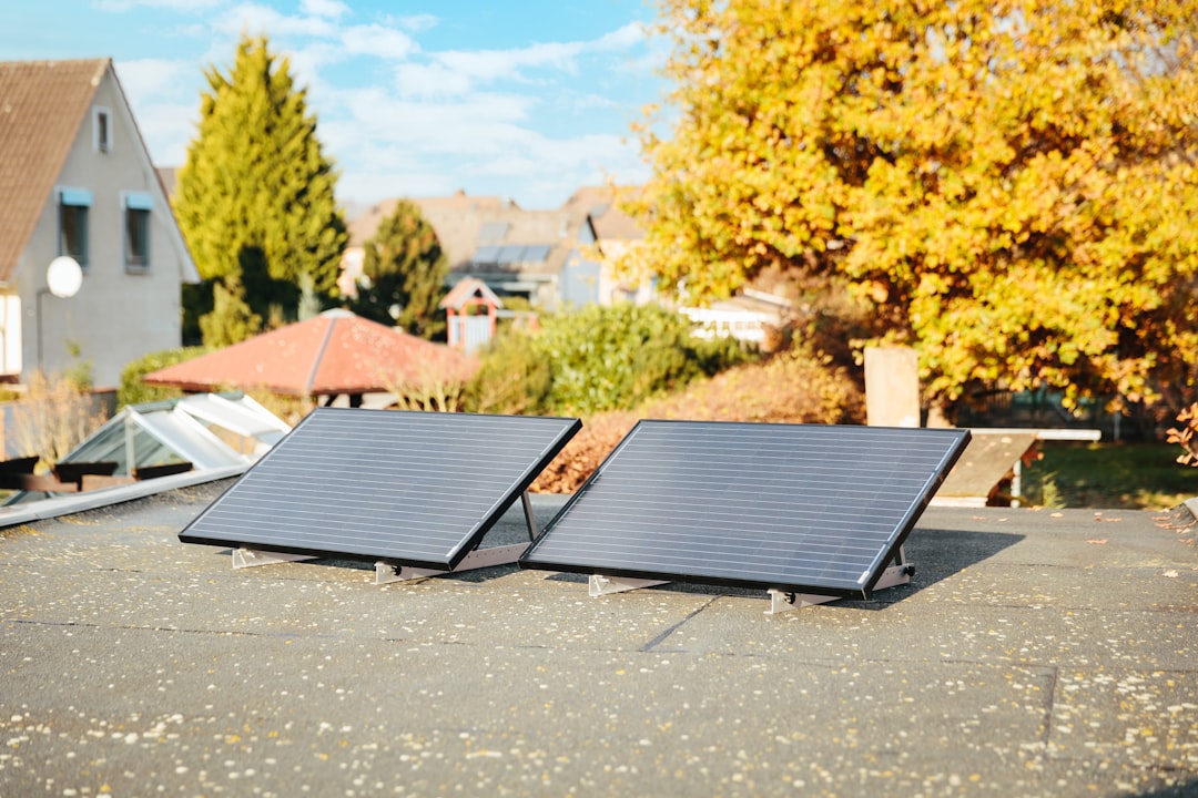 Two solar panels on a rooftop with autumn foliage