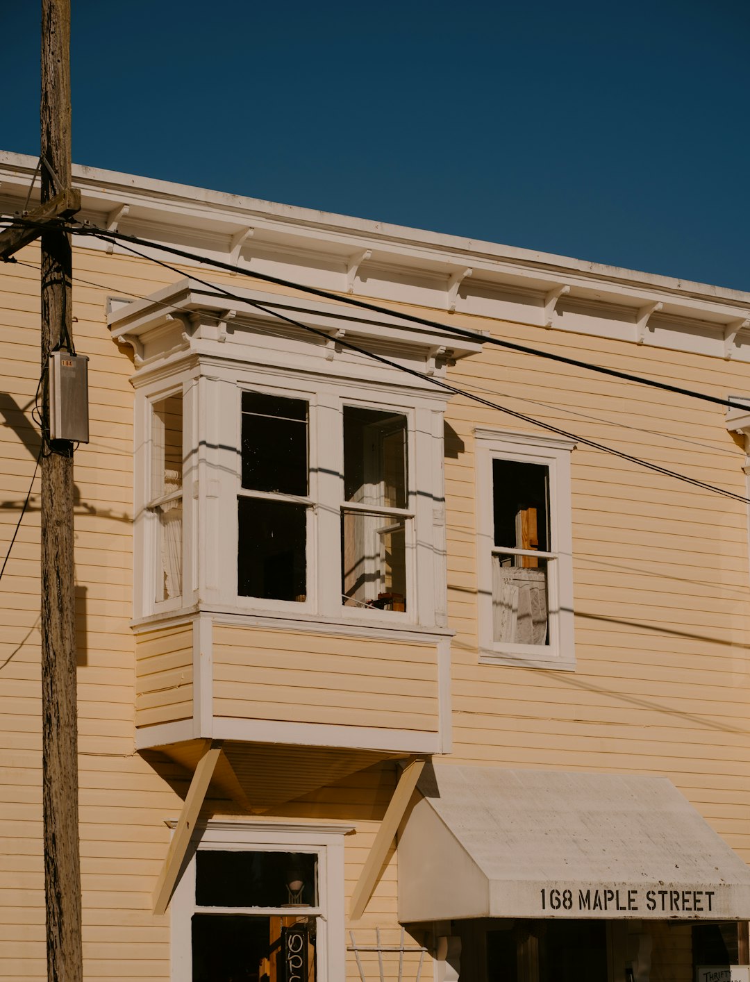 Yellow building with bay window and '168 maple street' sign