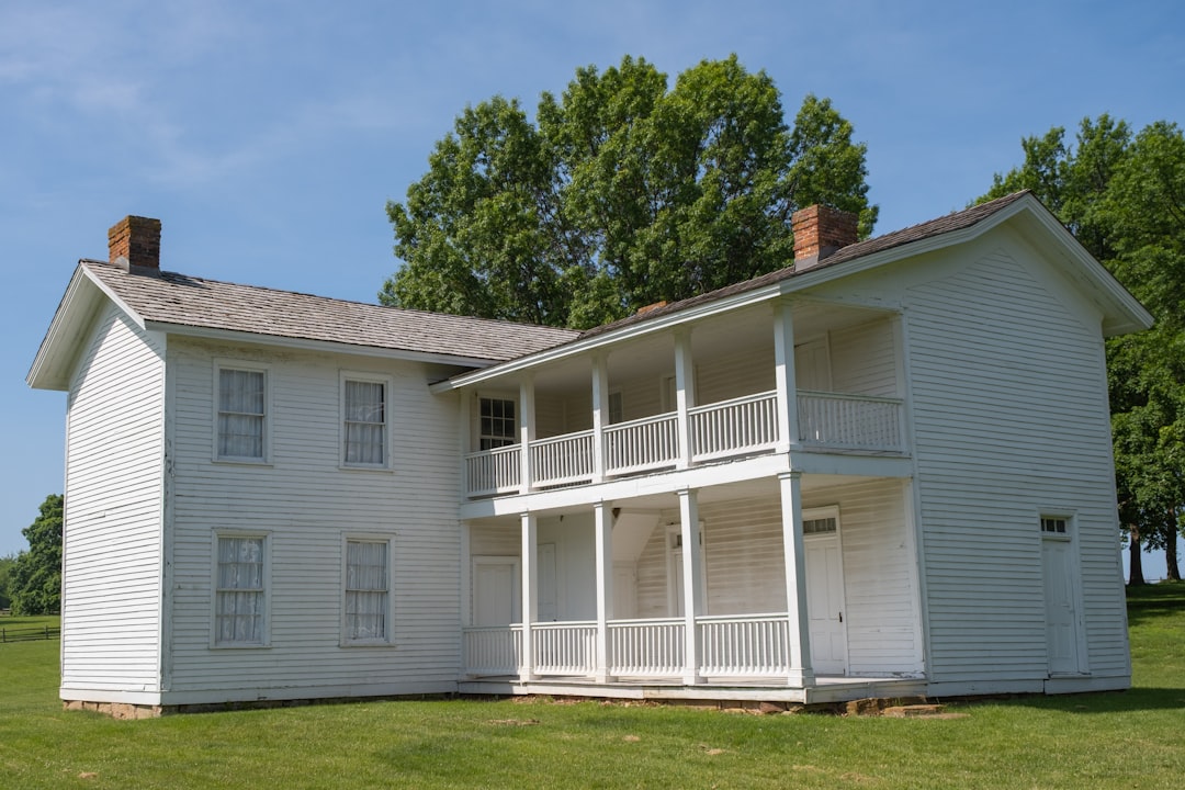 White two-story building with balconies against a blue sky.