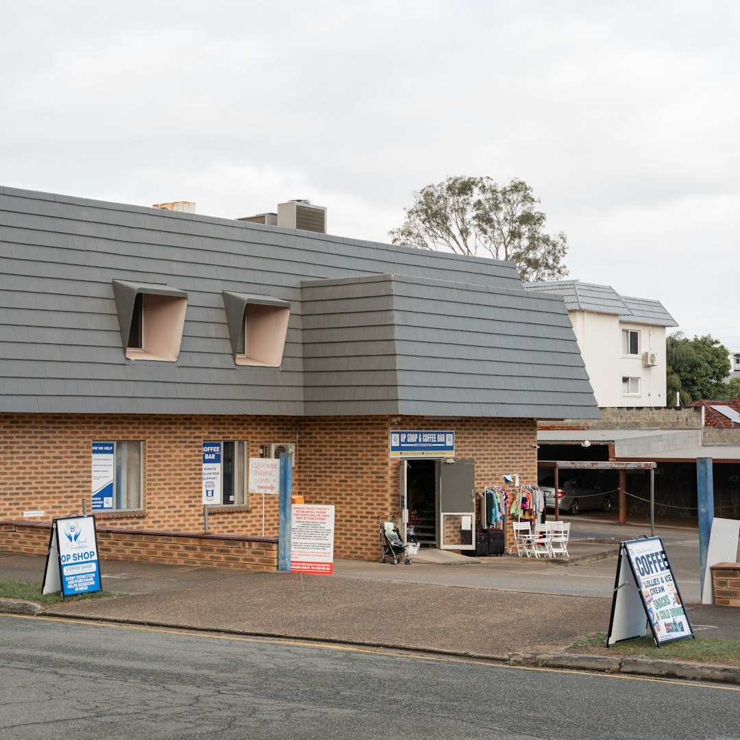 A brick building with a grey roof and signs outside