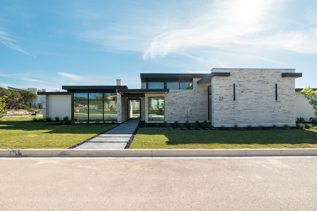Contemporary stone house with large windows and a green lawn.