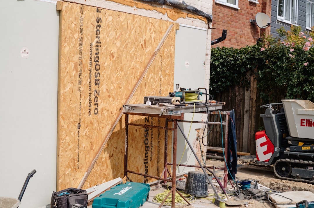 8e75dbd9667c40e982a5d6c11f65f332 Construction site with boarded-up wall and saw