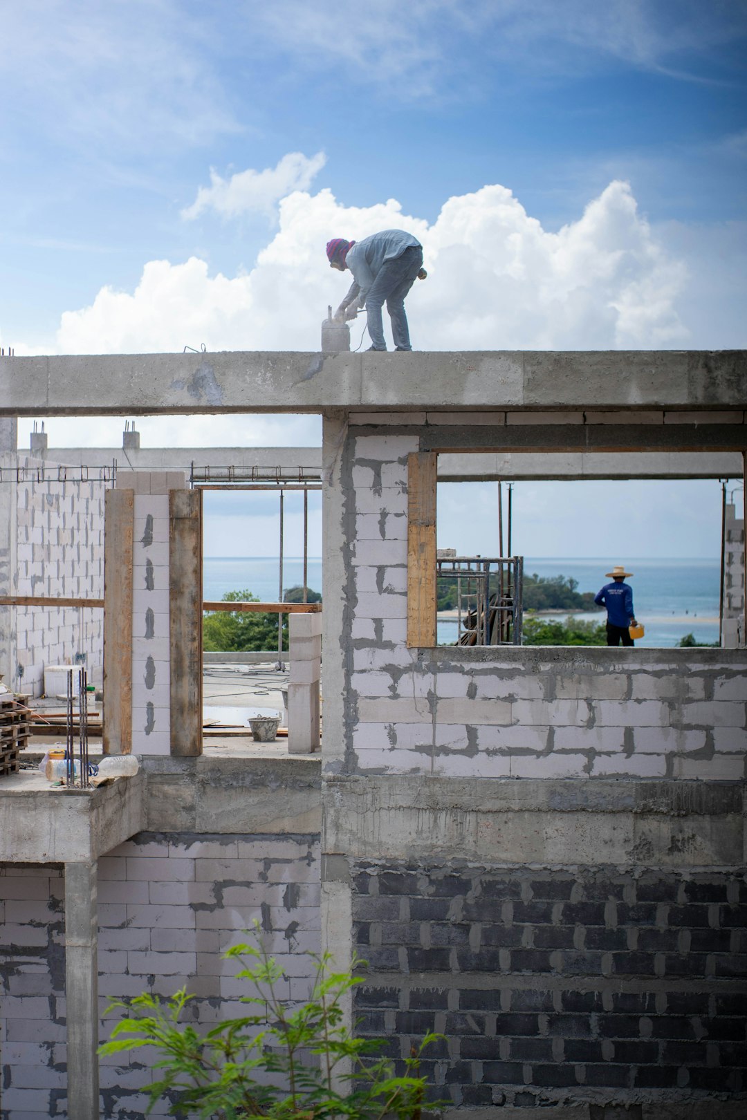 9096adb0a5ab43df871c911d34fcf078 Construction workers building a structure near the ocean.