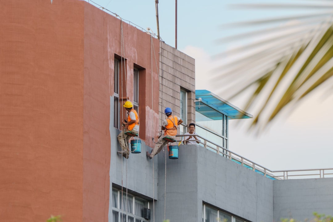 Workers suspended by ropes painting a building