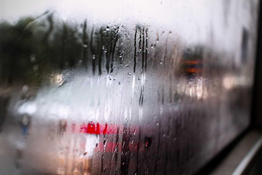 918aad4dde3e4f6291ddfb73f2325a7d Raindrops stream down a foggy window, blurring cars outside